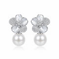 Front view of sculpted floral silver earrings with a suspended pearl drop on a white background.