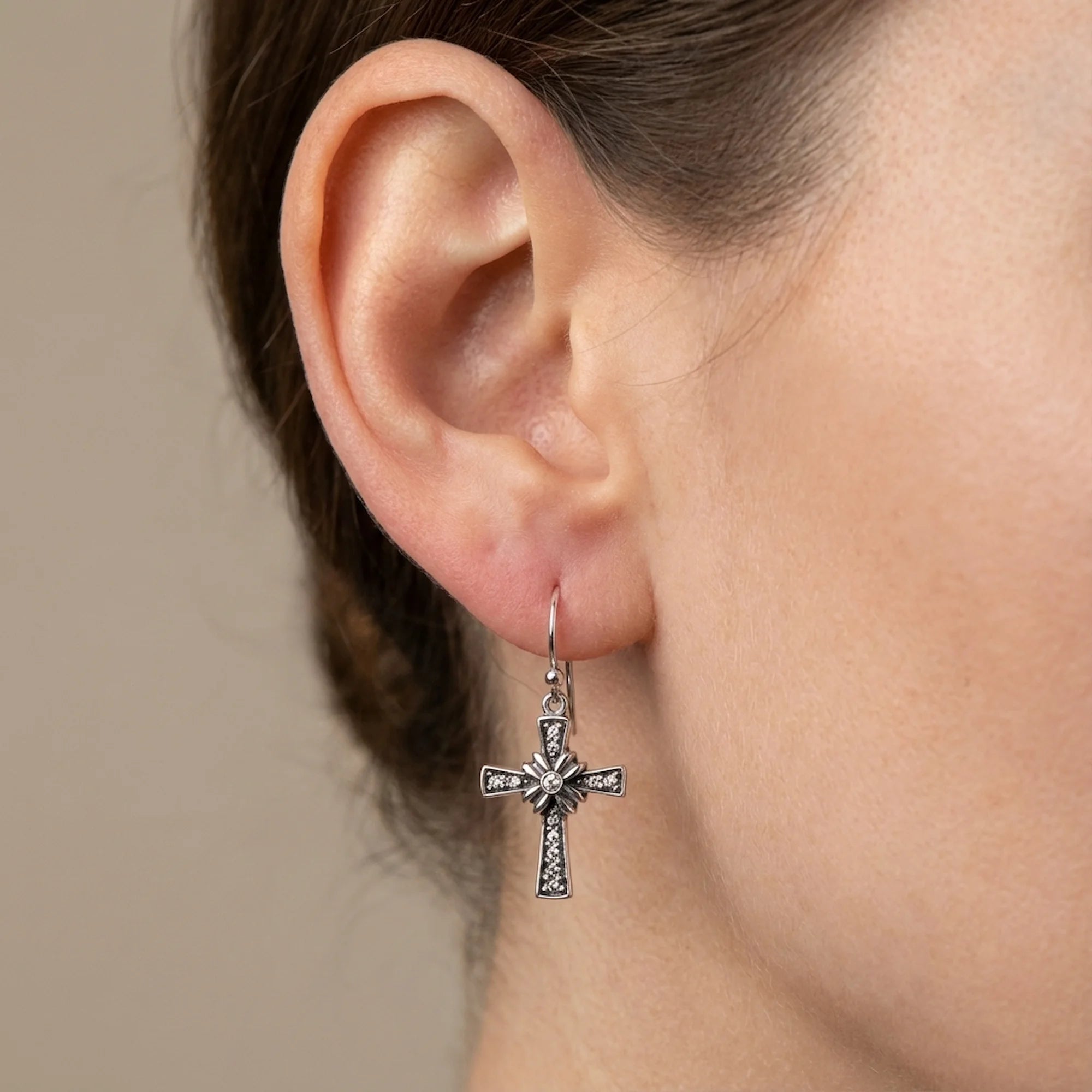 Floriated cross dangle earring worn, side profile — oxidised 925 sterling silver with rhinestones and floral centre