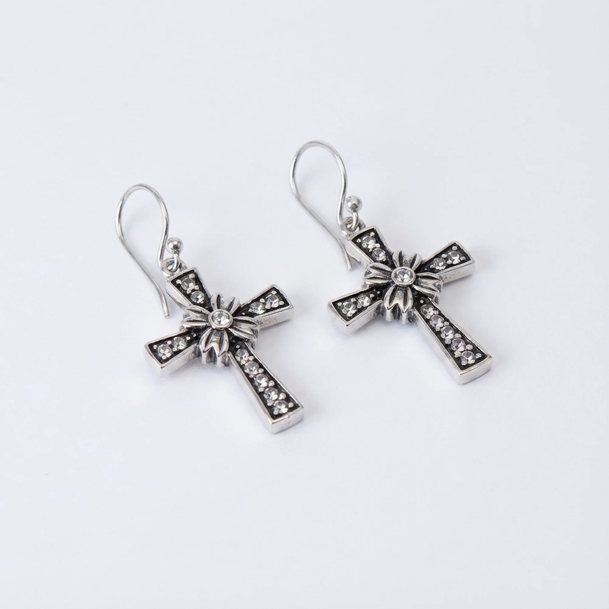 Floriated cross dangle earrings in oxidised 925 sterling silver, angled view — rhinestone pavé and floral starburst centre