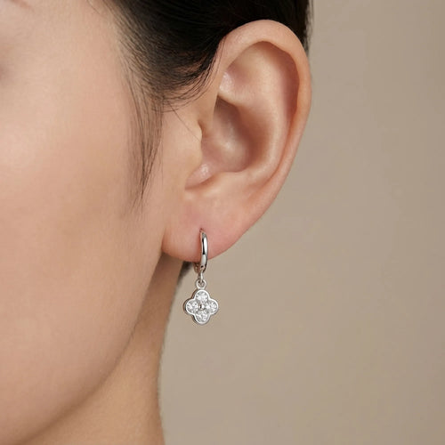 Woman wearing a silver four-leaf clover huggie hoop earring, in Luna Dura studio Dubai.
