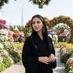 Model in black abaya wearing gold ginkgo leaf drop earrings at Dubai Miracle Garden, Burj Khalifa background