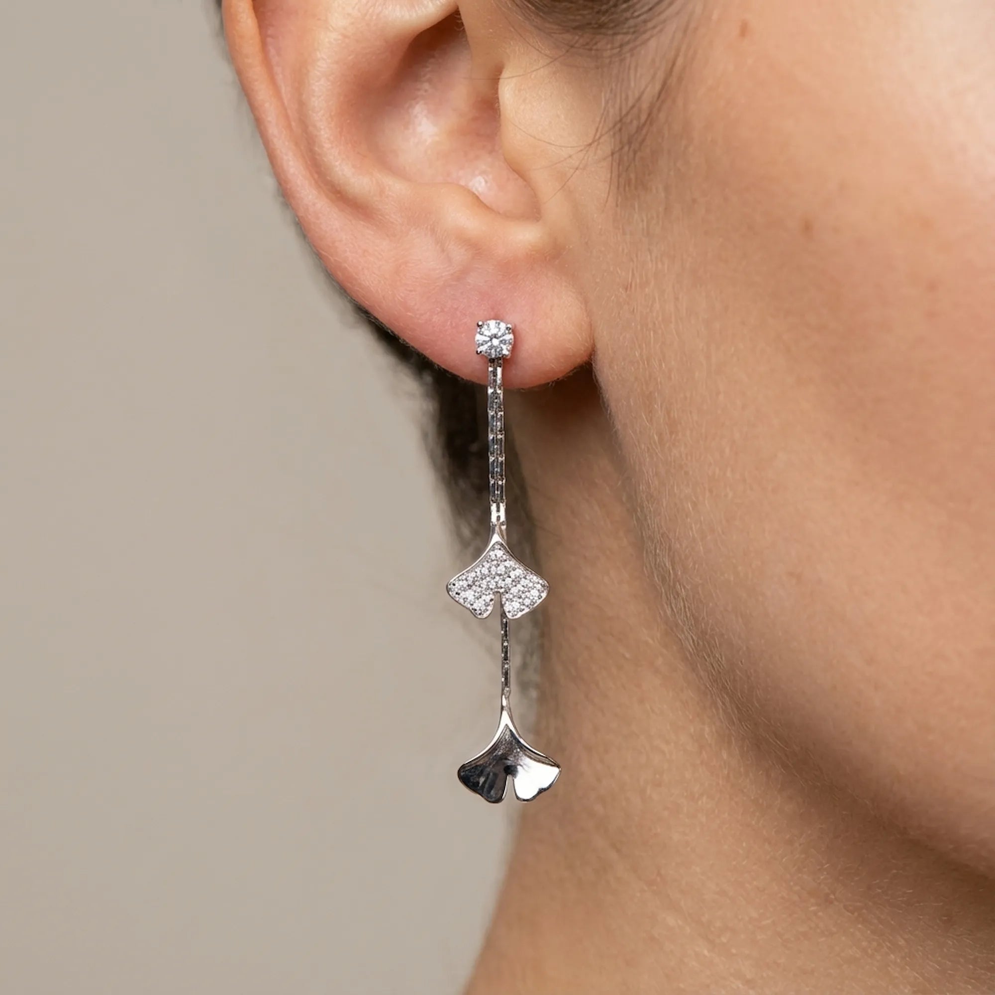 Ginkgo leaf drop earring in rhodium silver with pave CZ worn on model ear, cool finish detail