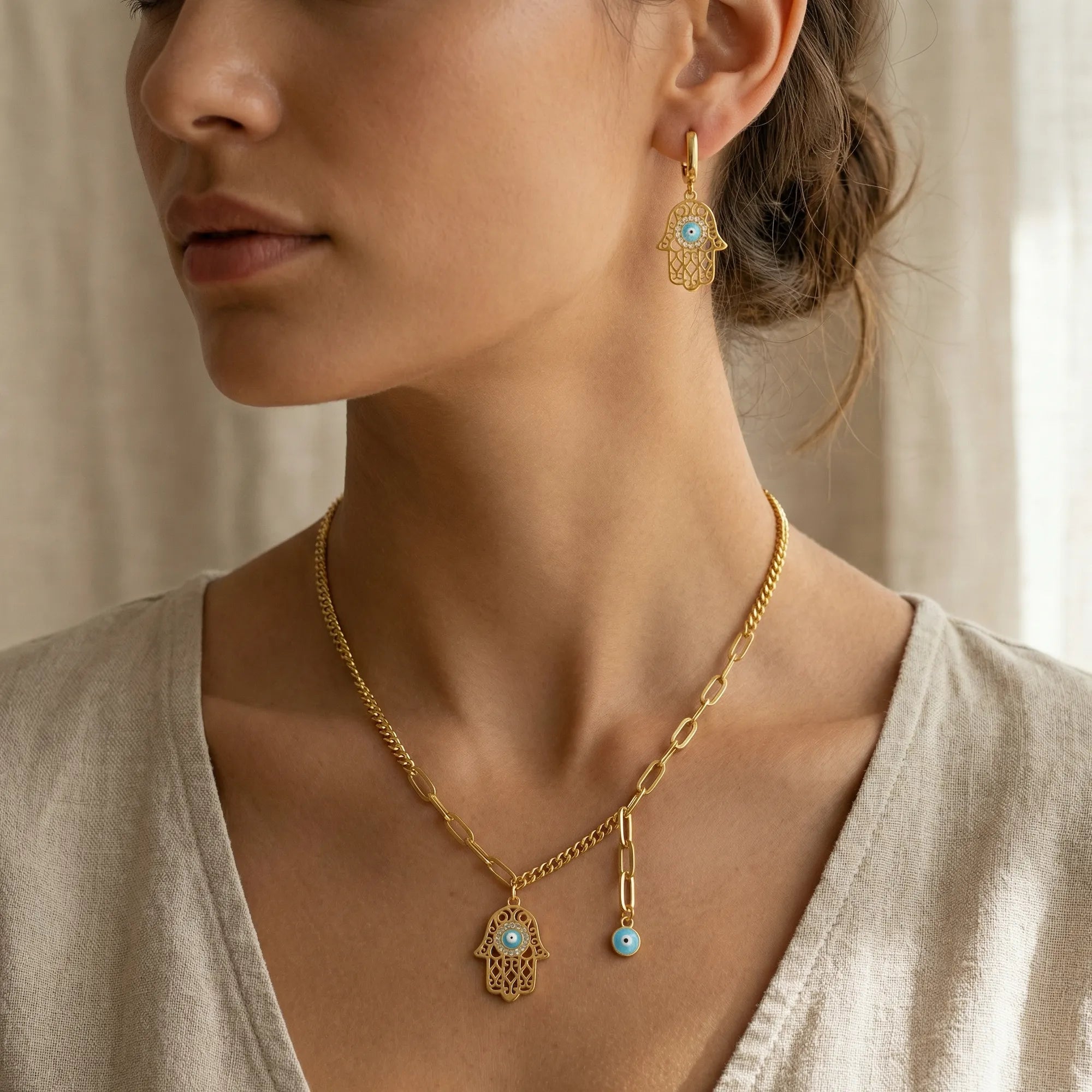 Gold Hamsa necklace and huggie earring worn on model, mixed-link chain with evil eye charm, Dubai UAE