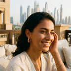 Woman wearing gold plated lattice hoop earrings with cubic zirconia, smiling outdoors in Dubai.