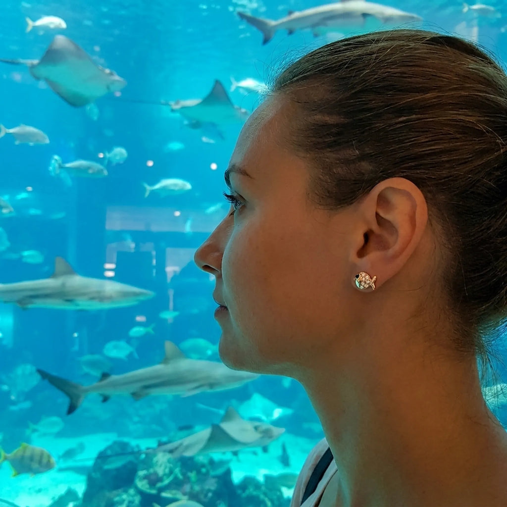 Goldfish stud earrings worn at Dubai Aquarium — 18K gold-plated 925 silver, fish tank background, Dubai Mall