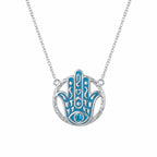Hamsa hand pendant necklace in 925 sterling silver with powder blue enamel and a sky blue topaz eye, Luna Dura Dubai.