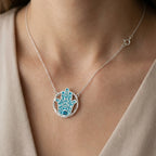 Woman wearing a powder blue Hamsa pendant necklace in 925 silver with sky blue topaz, Luna Dura Dubai.