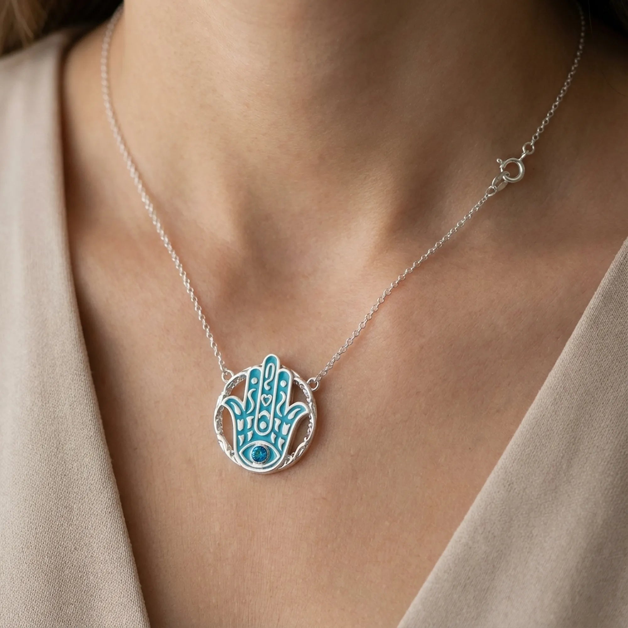 Woman wearing a powder blue Hamsa pendant necklace in 925 silver with sky blue topaz, Luna Dura Dubai.
