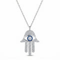 Hamsa evil eye pendant necklace in rhodium-plated 925 silver with full pavé white Cubic Zirconia and blue CZ halo, white background
