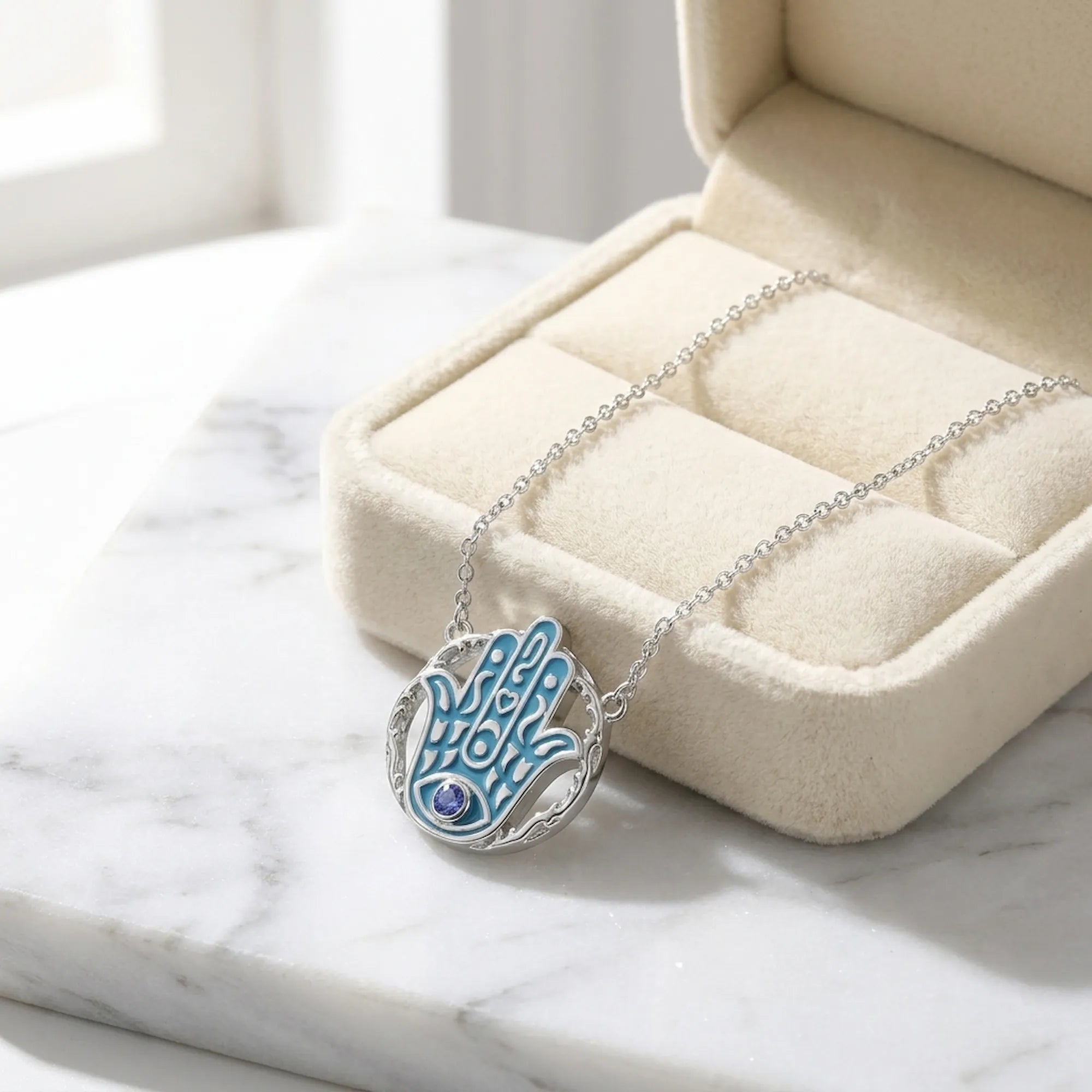 Azure blue Hamsa tanzanite pendant necklace in a cream velvet gift box, 925 sterling silver, Luna Dura Dubai.