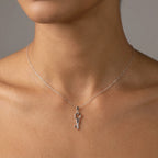 Close-up of silver heart key pendant at collarbone — open heart bow and key form in polished 925 sterling silver