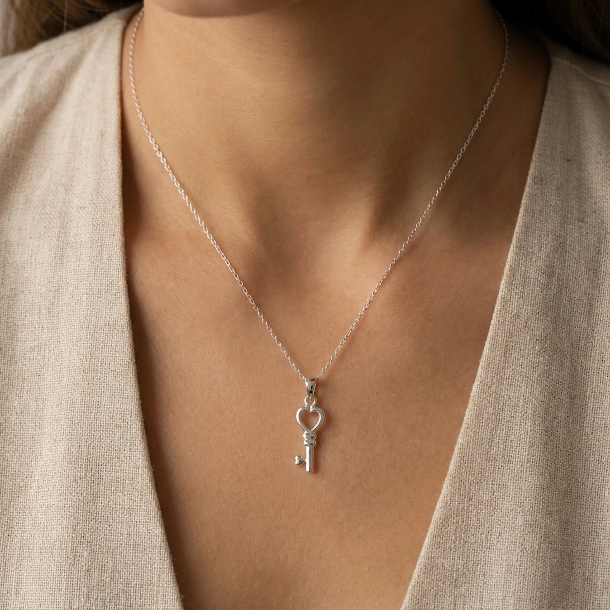 Heart key pendant necklace worn at collarbone on model in linen top — polished 925 sterling silver Dubai