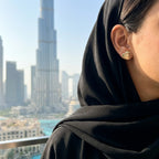 Hiam gold heart stud earring on model with black abaya and hijab — Burj Khalifa Dubai skyline background