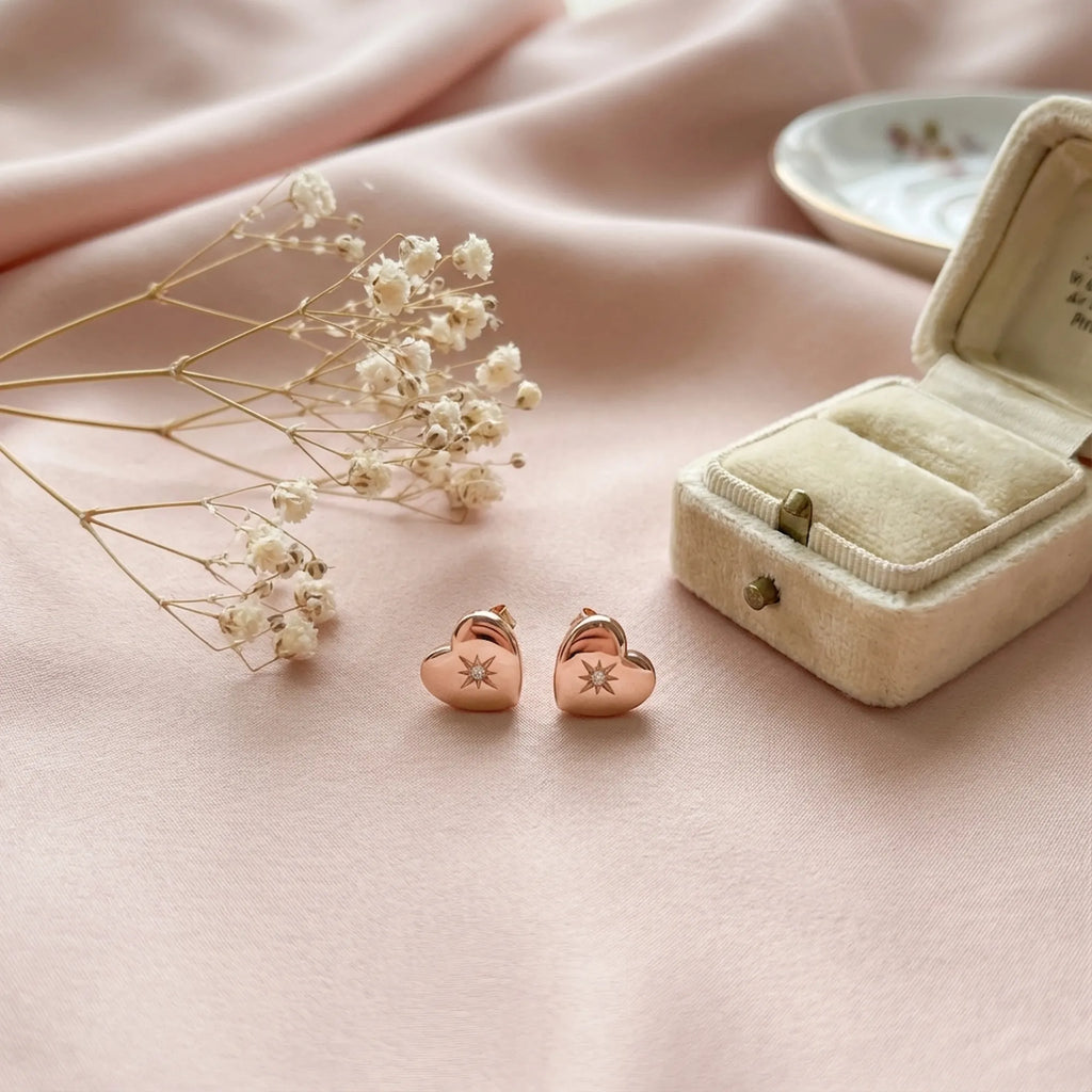Hiam rose gold heart stud earrings on pink satin beside velvet box and dried flowers — gifting presentation