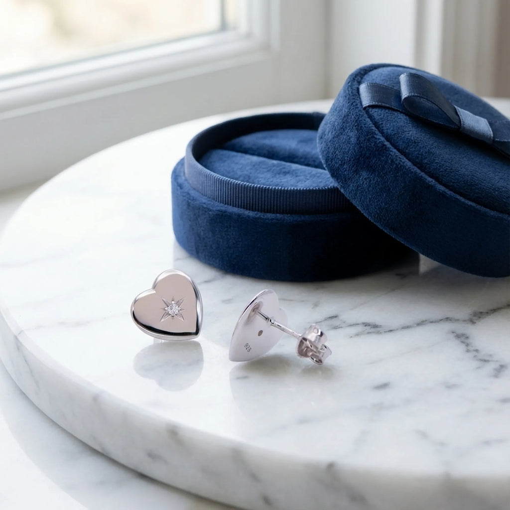 Hiam rhodium silver heart stud earrings on marble beside open navy velvet gift box — 925 sterling silver