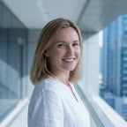 Woman wearing silver hoop earrings in clean minimalist mode in glass corridor with Dubai high-rise towers visible behind