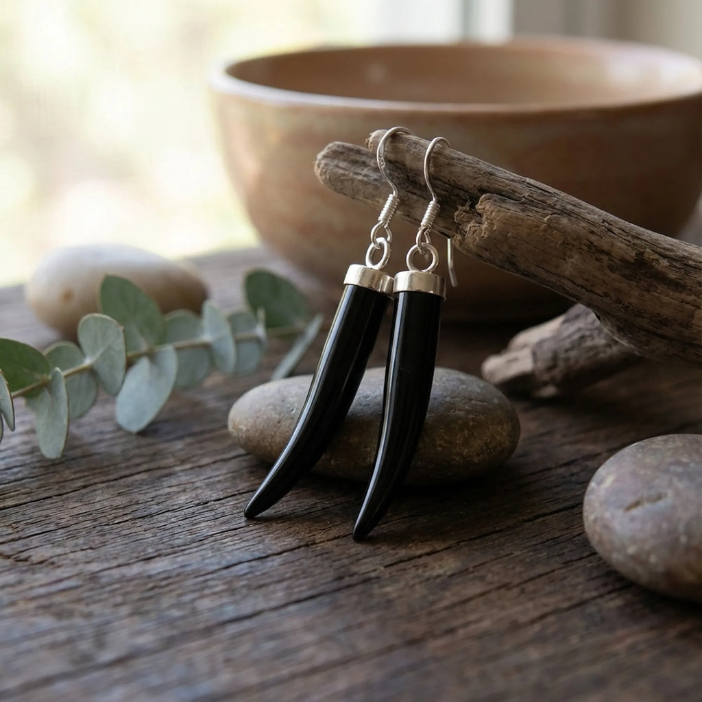 Black onyx horn dangle earrings on rustic wood with stones — 925 silver, natural stone earthy flat lay At Luna Dura SZR