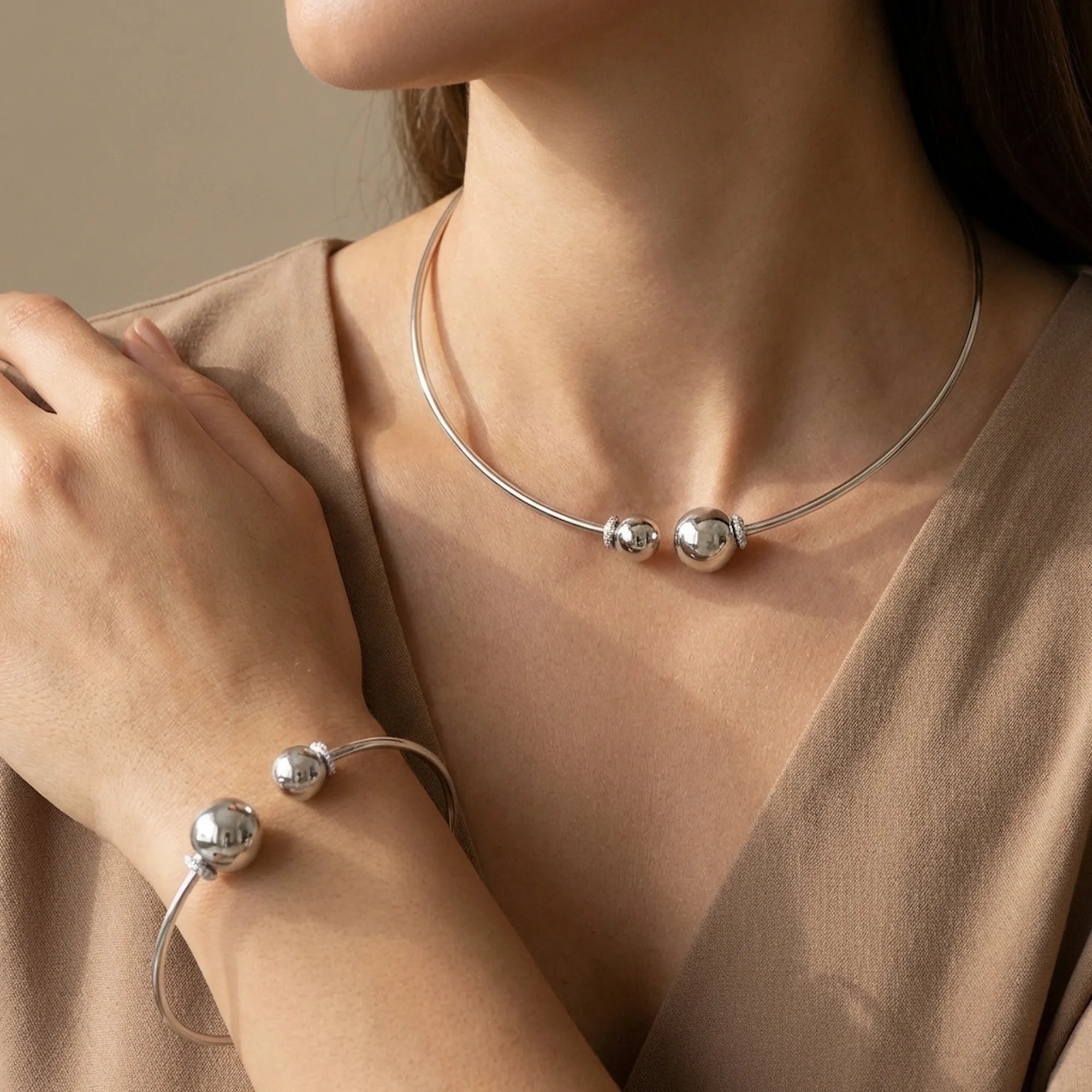 Fashion model demonstrating how to wear the sterling silver choker and bangle set with an elegant neutral v-neck outfit.
