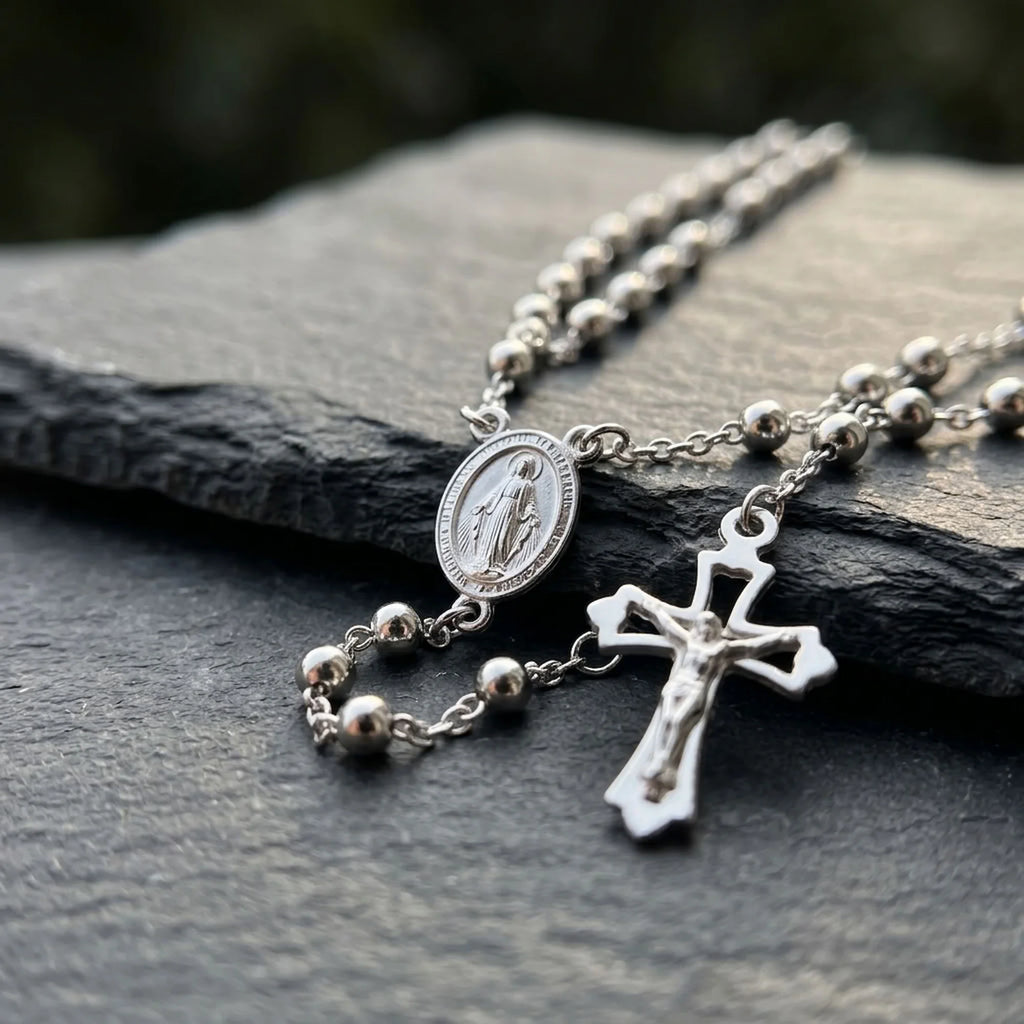 Close-up of Italian 925 silver rosary with oval Virgin Mary medal, polished bead chain and pierced crucifix with raised Christ figure.