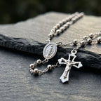 Close-up of Italian 925 silver rosary with oval Virgin Mary medal, polished bead chain and pierced crucifix with raised Christ figure.
