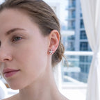 Rhodium silver jasmine flower stud earring on model's ear with Dubai glass building in background — botanical design