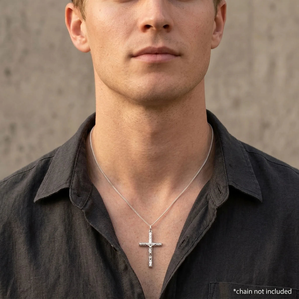 Man wearing a sterling silver crucifix pendant with raised Jesus figure, styling chain not included.