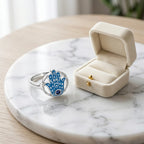 925 Sterling silver azure enamel hamsa ring with a tanzanite eye on marble beside a cream ring box Luna Dura Studio.