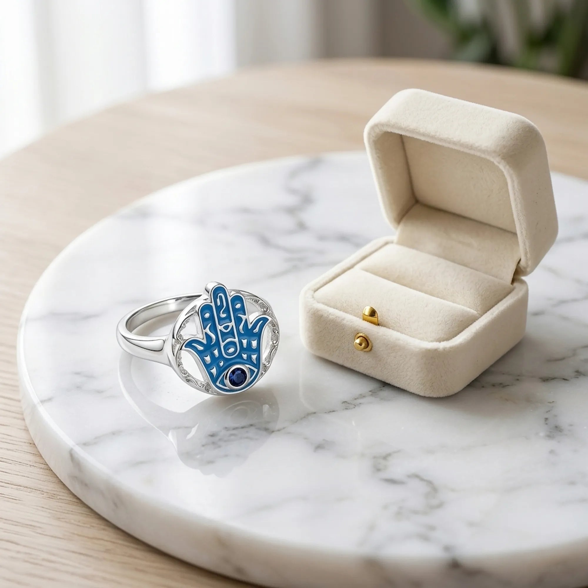 925 Sterling silver azure enamel hamsa ring with a tanzanite eye on marble beside a cream ring box Luna Dura Studio.