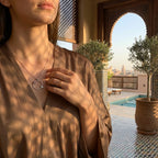 Woman in an elegant outdoor setting wearing the fashion 2026 ladybug necklace for everyday luxury.