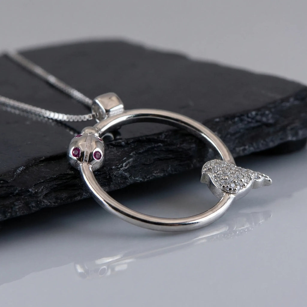 Macro detail of the red and white CZ gemstones set within the 925 sterling silver ladybug necklace.