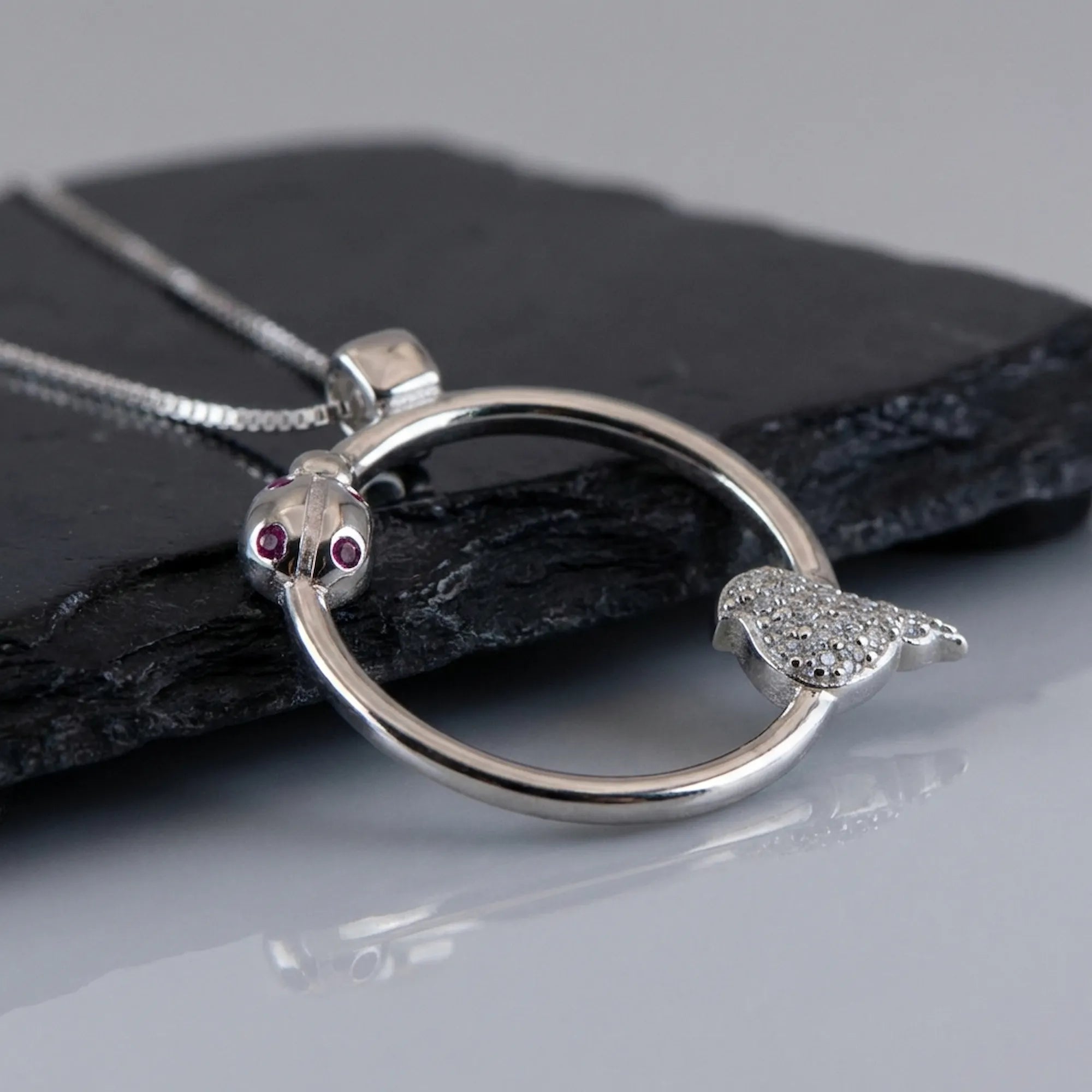 Macro detail of the red and white CZ gemstones set within the 925 sterling silver ladybug necklace.