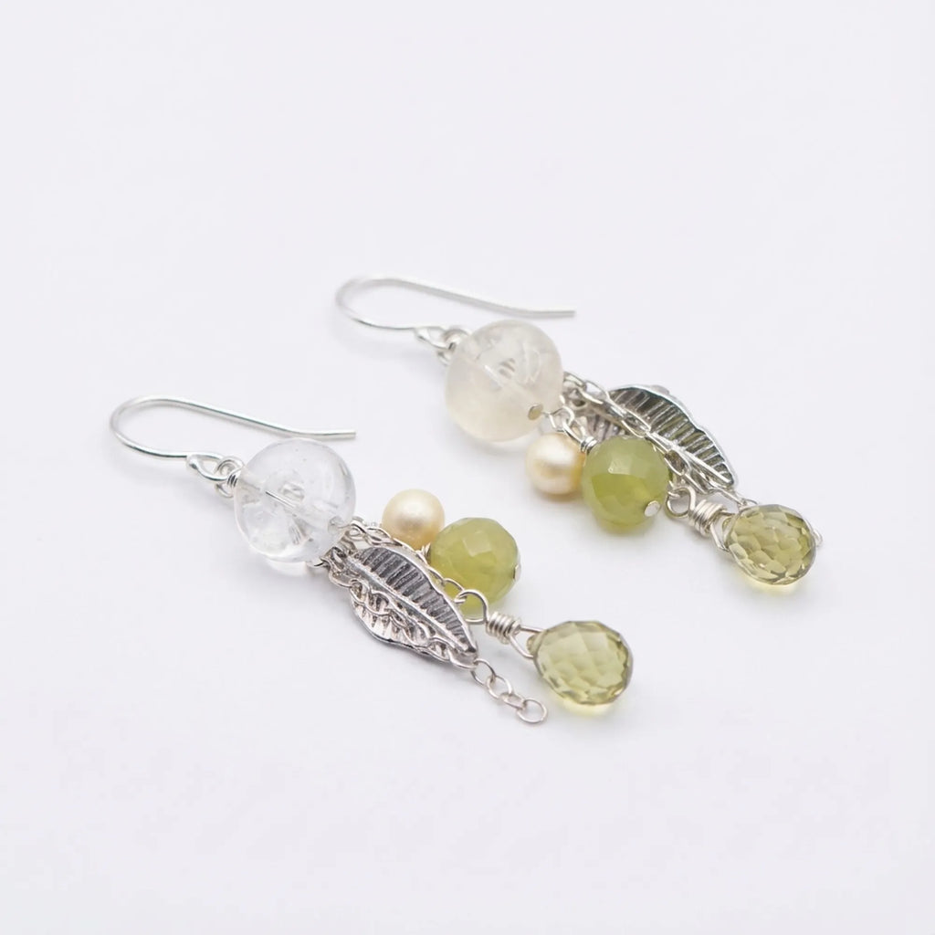 An angled view highlighting the cascading chains of these 925 sterling silver leaf chain drop earrings featuring lime green stones.