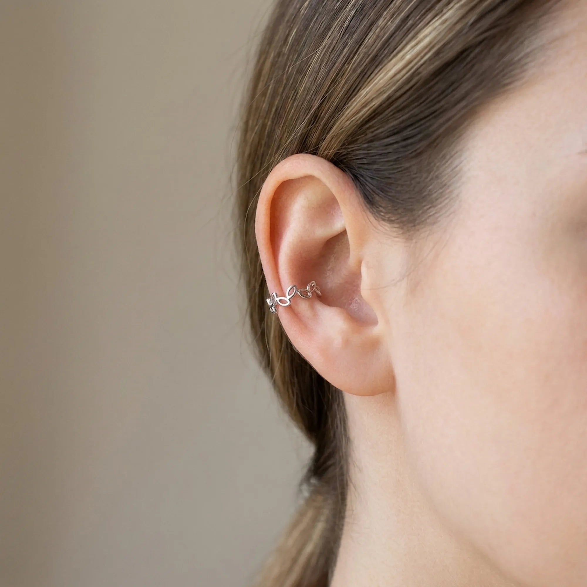 Model wearing a silver leaf-vine ear cuff on the conch with no piercing, Luna Dura Dubai.