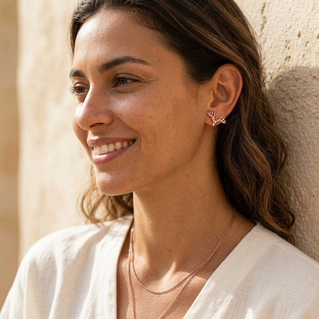 18K rose gold plated 925 sterling silver antler stud earrings worn by a woman outdoors in Dubai.