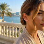 Stylish woman wearing a minimalist 925 sterling silver ear cuff while enjoying a sunny afternoon at a vibrant waterfront cafe in yas island.
