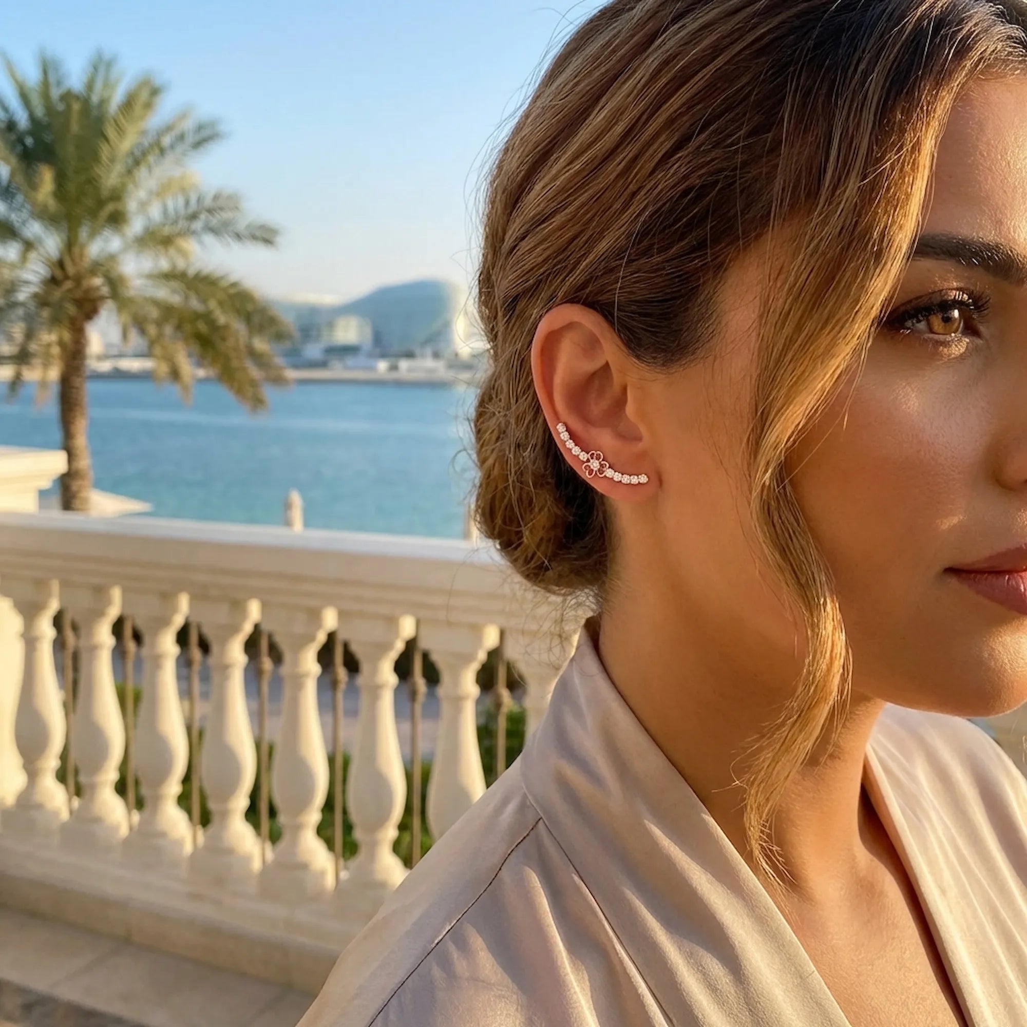 Stylish woman wearing a minimalist 925 sterling silver ear cuff while enjoying a sunny afternoon at a vibrant waterfront cafe in yas island.