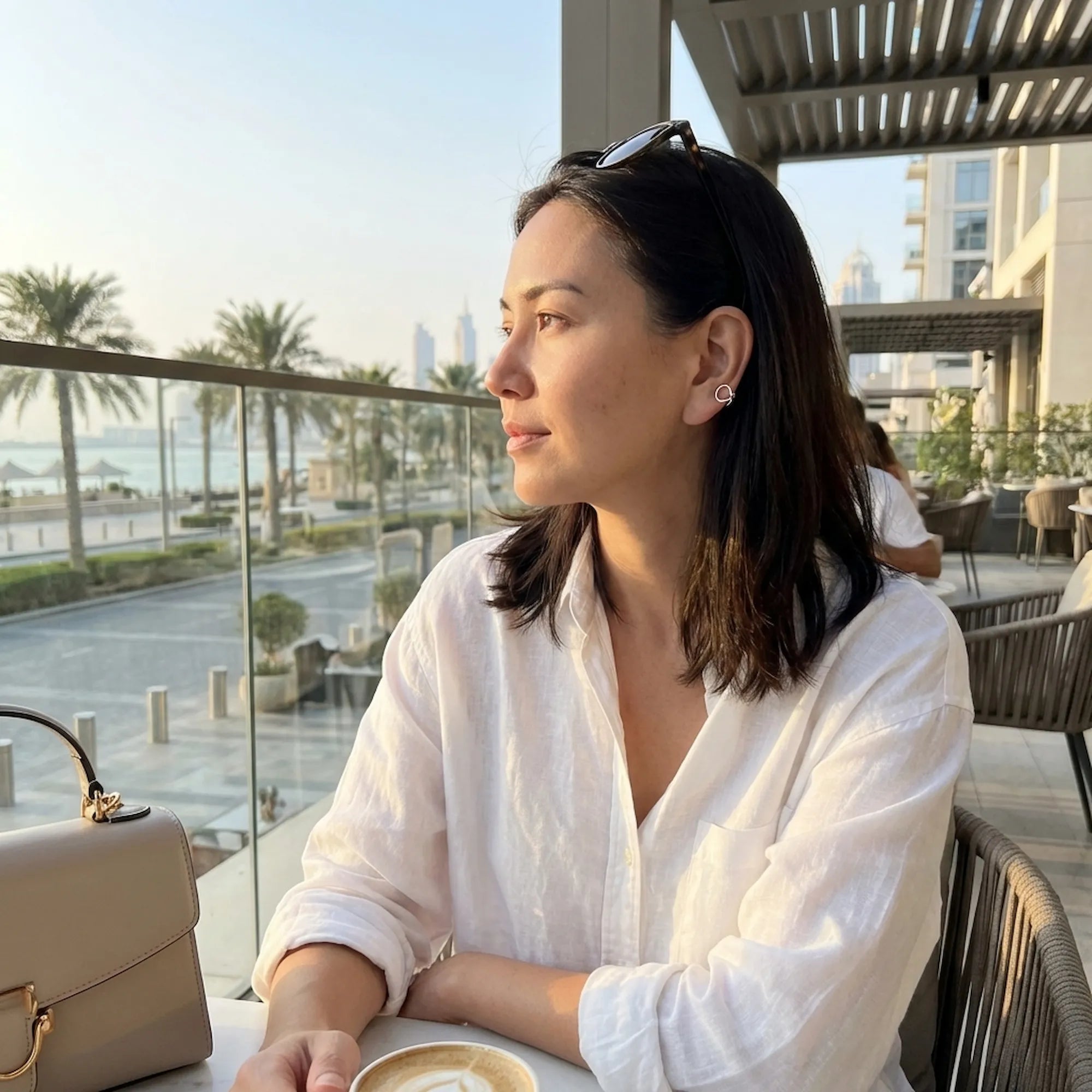 Woman wearing 925 silver ear cuff at Dubai waterfront cafe — no-piercing minimal style