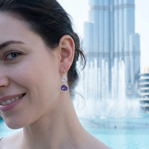 Woman wearing amethyst lotus dangle earrings by the Dubai Fountain and Burj Khalifa, Downtown Dubai.