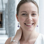 Smiling woman wearing 925 silver amethyst and white topaz lotus dangle earrings, Luna Dura Dubai.