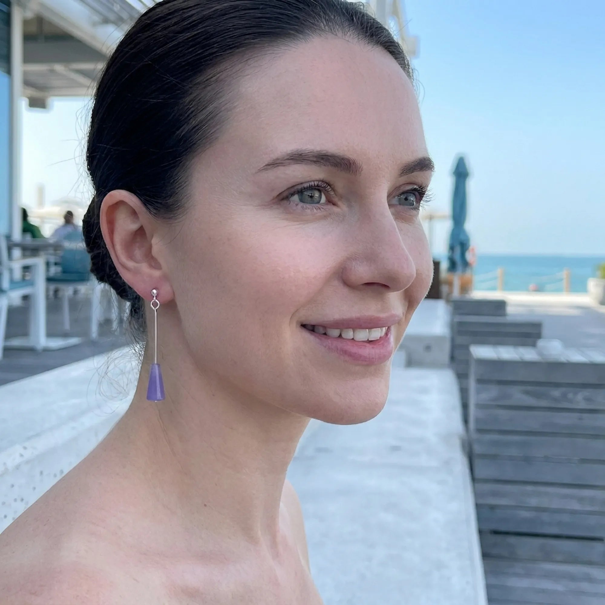 Model wearing amethyst purple lucite cone drop earrings at Dubai waterfront — geometric silver drop earrings UAE