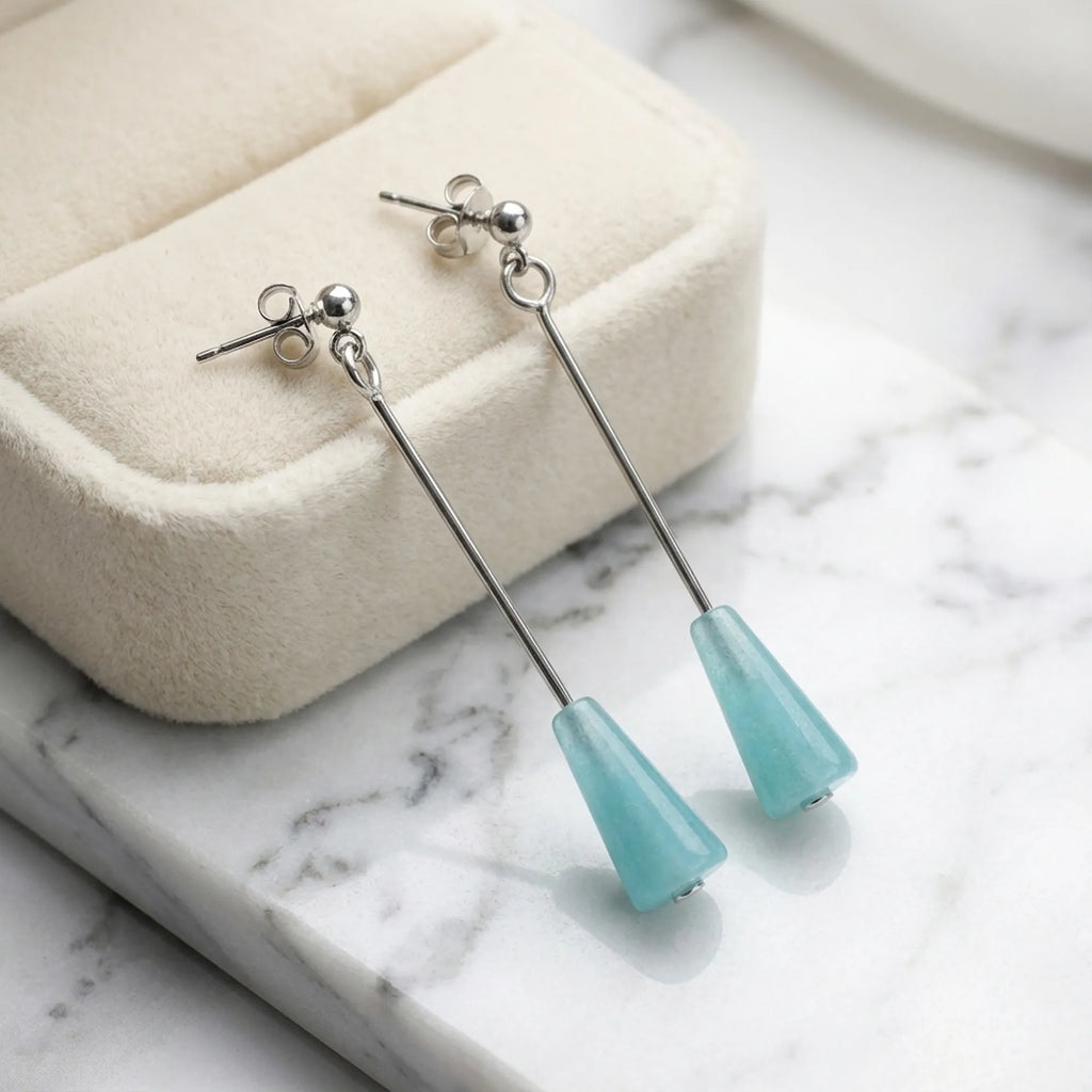 Aqua blue lucite cone drop earrings beside cream velvet jewelry box on marble — gift jewelry Dubai UAE