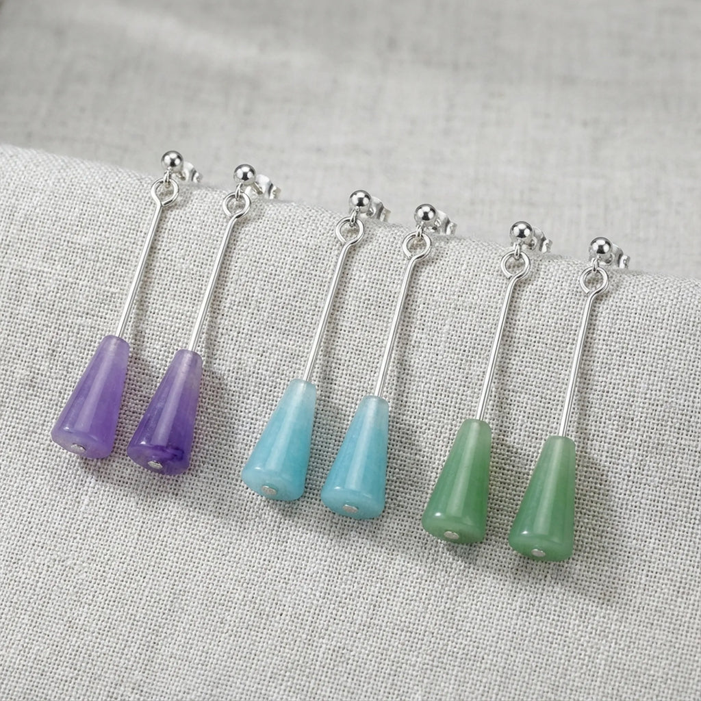 All three lucite cone drop earrings flat lay on linen — amethyst purple, aqua blue, sage green with 925 silver bars