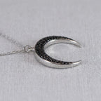 Side angle view of the Luna Dura sterling silver crescent moon pendant, showcasing the pave-set black zircon stones and high-polish finish