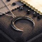 Macro close-up of pave-set black zircon crystals on a 925 sterling silver crescent pendant, highlighting the professional bezel setting
