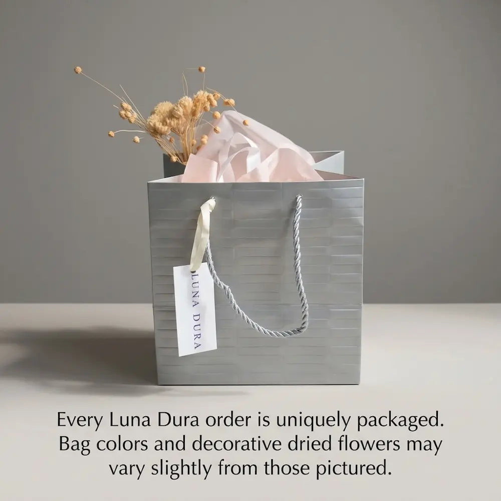 Luna Dura jewellery gift packaging with silver-toned bag, tissue paper and dried flowers; presentation may vary.