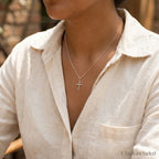 Woman wearing a mini 925 silver cross necklace with included rolo chain.