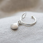 Macro detail shot of the minimalist silver ear cuff highlighting the intricate ridges on the sterling silver sea shell dangle charm.