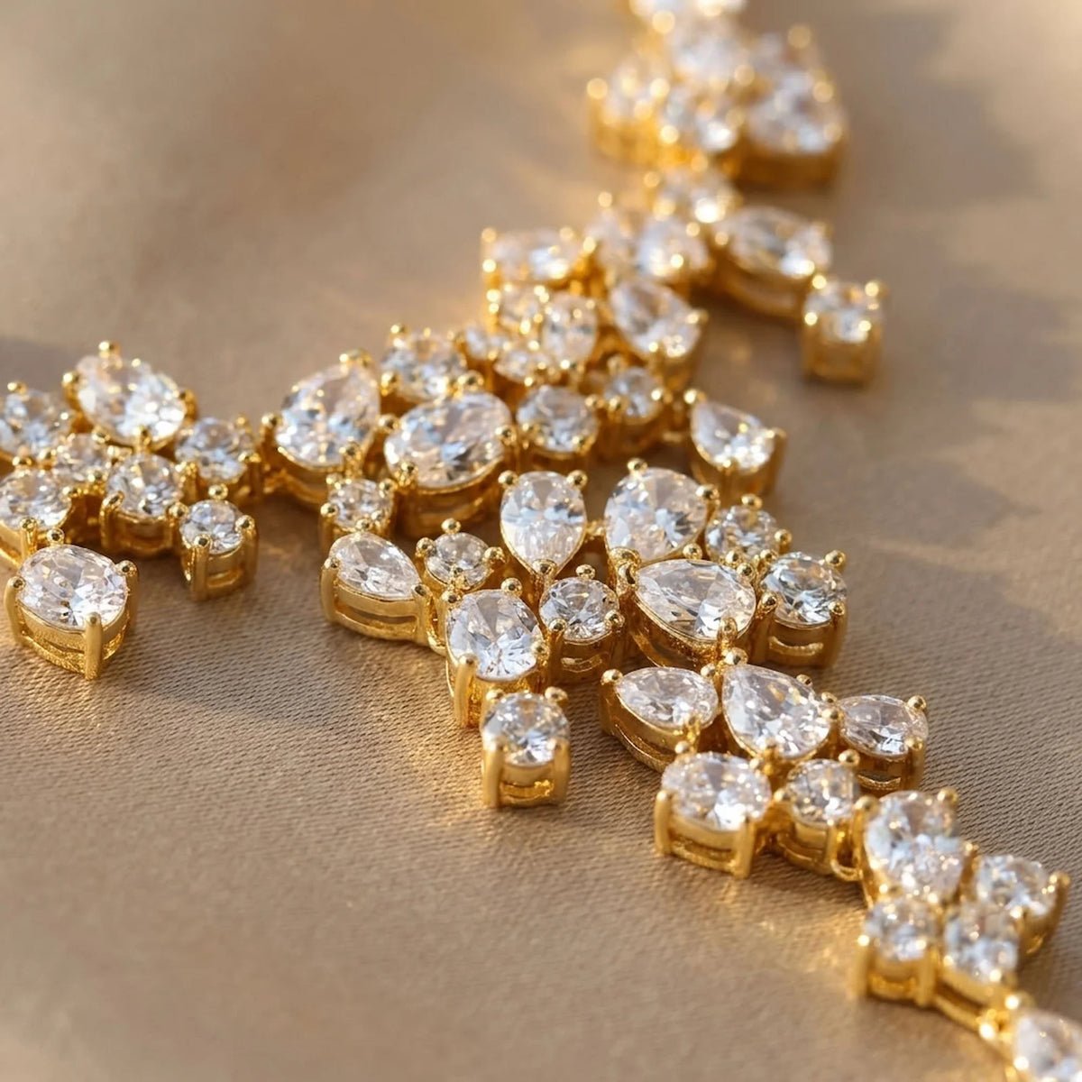 Macro view of an 18k gold-plated cubic zirconia waterfall necklace showing mixed-cut stones on silk fabric in Dubai.