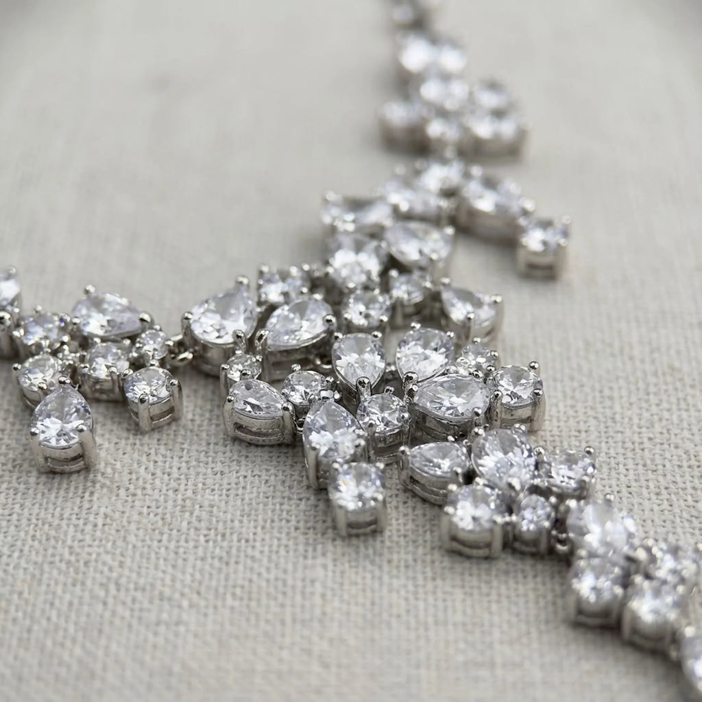 Macro view of a rhodium-plated cubic zirconia waterfall necklace showing mixed-cut stones on fabric in Dubai.