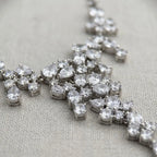 Macro view of a rhodium-plated cubic zirconia waterfall necklace showing mixed-cut stones on fabric in Dubai.